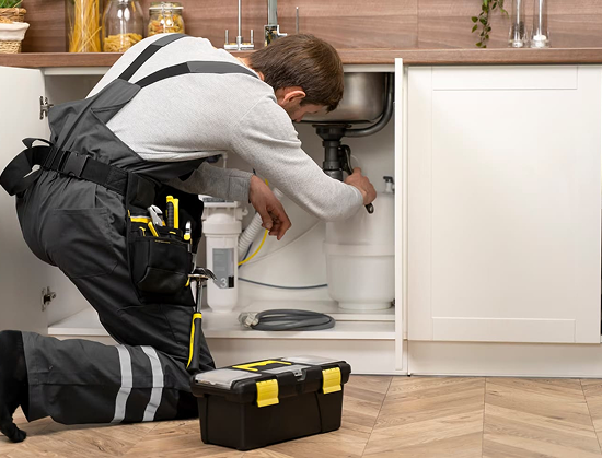 man wrenches the sink pipes